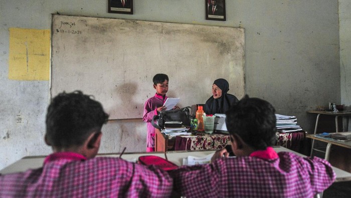 Guru memeberi materi pelajaran kepada siswa kelas IV di ruang perpustakaan yang dijadikan kelas di SDN 109 Desa Ladang Panjang, Muaro Jambi, Jambi, Jumat (17/1/2025). SD tertua di Desa Ladang Panjang, dibangun tahun 1983 itu memiliki keterbatasan ruang kelas sehingga terpaksa memanfaatkan ruang perpustakaan yang rusak untuk kegiatan belajar mengajar selama hampir 20 tahun. ANTARA FOTO/Wahdi Septiawan/Spt.