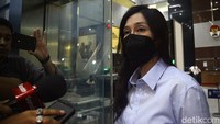 Maria mengenakan pakaian kemeja biru muda. Dia juga datang mengenakan masker hitam yang menutupi wajahnya.  