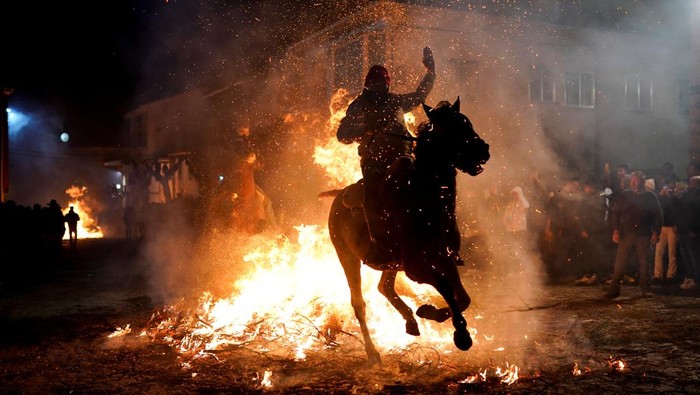 A man rides a horse through flames during the annual 