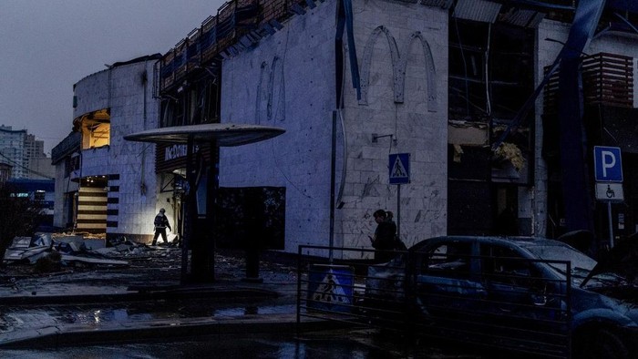 A firefighter shines a flashlight as he searches the debris of a damaged metro station and Mcdonalds, following a rocket attack in Kyiv, on January 18, 2025, amid the Russian invasion of Ukraine. (Photo by Tetiana DZHAFAROVA / AFP)