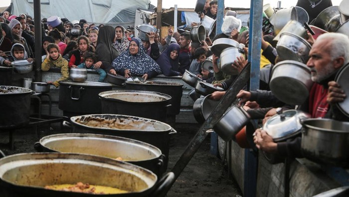 Palestinians gather to receive food cooked by a charity kitchen, before a ceasefire between Hamas and Israel takes effect, in Khan Younis, in the southern Gaza Strip, January 17, 2025. REUTERS/Hatem Khaled