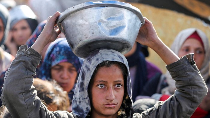 Palestinians gather to receive food cooked by a charity kitchen, before a ceasefire between Hamas and Israel takes effect, in Khan Younis, in the southern Gaza Strip, January 17, 2025. REUTERS/Hatem Khaled