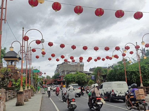 Pengendara melintas di Jalan Gajah Mada, Denpasar, yang dihiasi lampion merah, Sabtu (18/1/2025). Lampion dipasang menjelang perayaan Imlek 2025 (Karsiani Putri/detikBali).