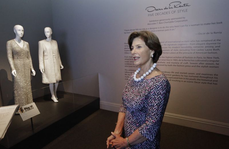 This July 17, 2014 photo shows former first lady Laura Bush speaks during an interview next to her Oscar de la Renta dress and coat she wore to the swearing-in ceremony at her husbands 2005 inauguration that are on display in Dallas. The ensembles are among more than 60 featured in a new retrospective on de la Rentas career that opens Saturday at the George W. Bush Library and Museum. Oscar de la Renta: Five Decades of Style, which runs through Oct. 5, features designs worn by everyone from celebrities to socialites to first ladies. (AP Photo/LM Otero)