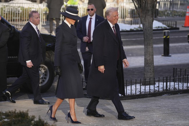 Berbasis di New York City, Adam Lippes mendesain setelan mantel double breasted. Di dalam luaran tersebut, terdapat atasan berkerah putih. Melania kemudian melengkapi gayanya dengan sepatu dan sarung tangan senada. (Foto: AP Photo/Matt Rourke)