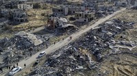 Mereka berjalan dari pengungsian melewati kota yang sudah runtuh total. (AP Photo/Jehad Alshrafi)