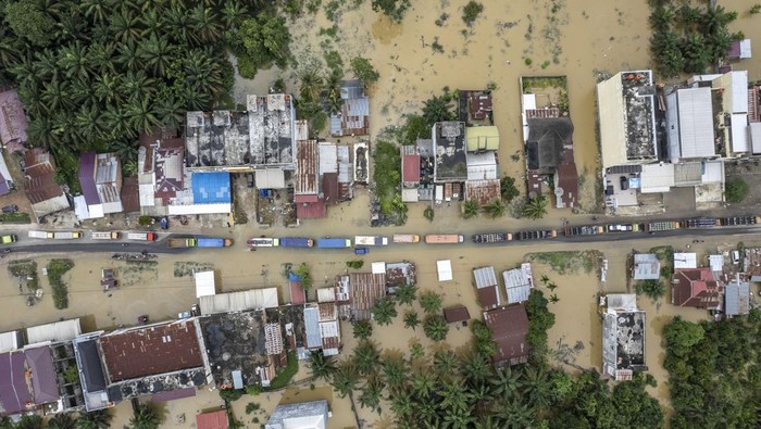 Foto udara sejumlah kendaraan terjebak kemacetan di Jalan Lintas Sumatera akibat banjir di Merlung, Tanjung Jabung Barat, Jambi, Senin (20/1/2025). Banjir akibat meluapnya Sungai Pengabuan di daerah itu menyebabkan jalan nasional yang menghubungkan Jambi dengan Riau itu lumpuh total sejak Minggu (19/1/2025) sore dengan ketinggian air mencapai 150 sentimeter. ANTARA FOTO/Wahdi Septiawan/rwa.