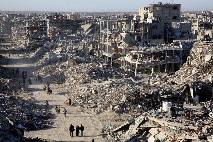 Palestinians walk past the rubble of houses and buildings destroyed during the war, following a ceasefire between Israel and Hamas, in Rafah in the southern Gaza Strip, January 20, 2025. REUTERS/Hatem Khaled     TPX IMAGES OF THE DAY