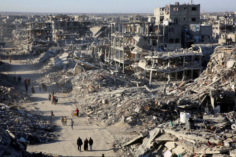 Palestinians walk past the rubble of houses and buildings destroyed during the war, following a ceasefire between Israel and Hamas, in Rafah in the southern Gaza Strip, January 20, 2025. REUTERS/Hatem Khaled     TPX IMAGES OF THE DAY