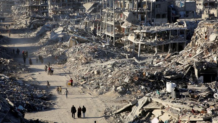 Palestinians walk past the rubble of houses and buildings destroyed during the war, following a ceasefire between Israel and Hamas, in Rafah in the southern Gaza Strip, January 20, 2025. REUTERS/Hatem Khaled TPX IMAGES OF THE DAY