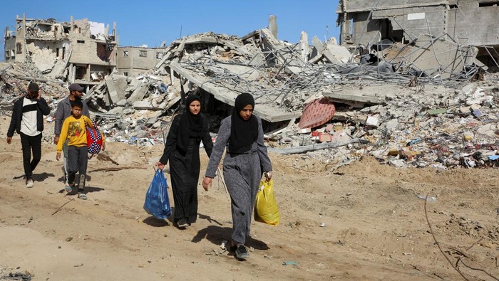 Palestinians walk past the rubble of houses and buildings destroyed during the war, following a ceasefire between Israel and Hamas, in Rafah in the southern Gaza Strip, January 20, 2025. REUTERS/Hatem Khaled     TPX IMAGES OF THE DAY