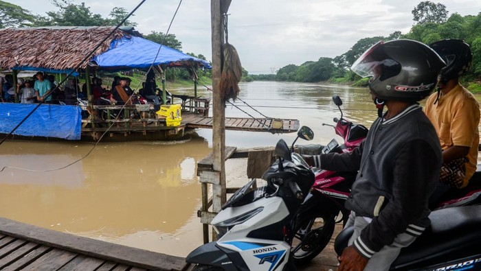 Pengendara sepeda motor menaiki perahu eretan menyeberangi sungai Ciujung di Kragilan, Kabupaten Serang, Banten, Senin (20/1/2025). Warga setempat terpaksa menggunakan perahu eretan bertarif Rp2.000 itu sebagai moda penyeberangan untuk melintasi Sungai Ciujung guna mempersingkat jarak tempuh karena tidak adanya akses jembatan penyeberangan di wilayah tersebut. ANTARA FOTO/Muhammad Bagus Khoirunas/rwa.