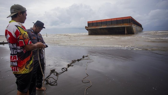 Polisi dibantu warga berusaha mengikat tongkang yang terdampar di Pantai Tiris, Pasekan, Indramayu, Jawa Barat, Senin (20/1/2025).