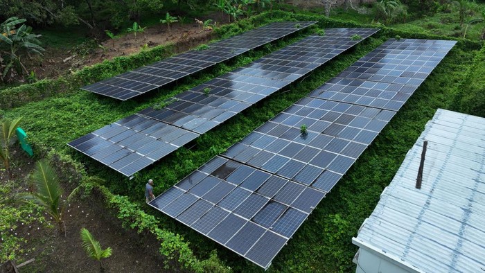 Warga berjalan di area pembangkit listrik tenaga surya (PLTS) yang rusak di Desa Lakarama, Kecamatan Towea, Muna, Sulawesi Tenggara, Senin (20/1/2025). Menurut pemerintah desa setempat PLTS 100 kWp bantuan dari Kementerian ESDM tahun 2015 itu yang selama ini menjadi sumber listrik bagi 1.287 warga di pulau muna tersebut sejak lima tahun lalu sudah tidak bisa berfungsi normal akibat kerusakan pada baterai. ANTARA FOTO/Jojon/tom.