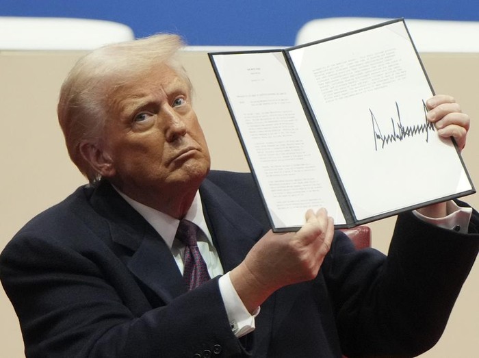 President Donald Trump holds up an executive order after signing it at an indoor Presidential Inauguration parade event in Washington, Monday, Jan. 20, 2025. (AP Photo/Matt Rourke)
