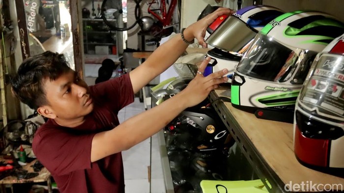 Eggi saat menunjukkan helm hasil reparasi di tempat bisnisnya.