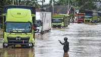 Petugas memandu jalannya arus lalu lintas saat banjir menggenangi Jalan Lintas Sumatera, Merlung, Jambi, Senin (20/1/2025). 