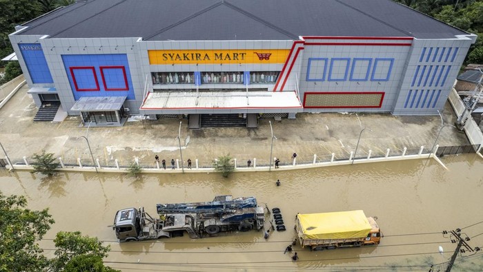 Foto udara petugas mobil derek mengevakuasi sebuah truk yang terjebak banjir di Jalan Lintas Sumatera, Merlung, Jambi, Senin (20/1/2025). Arus lalu lintas di jalan nasional yang sempat lumpuh total selama lebih dari 24 jam atau sejak Minggu (19/1/2025) sore akibat banjir setinggi 150 sentimeter dan terjebaknya dua buah mobil di tengah-tengah banjir itu sudah berhasil dilalui dengan sistem buka tutup. ANTARA FOTO/Wahdi Septiawan.