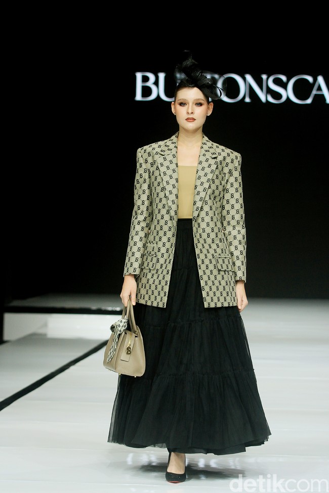 Monogram ‘B’ telah menjadi ciri khas koleksi busana Buttonscarves. Memasuki tahun ke-9, jenama yang didirikan Linda Anggrea ini mengemasnya dengan tampilan baru. Monogram dari logo Buttonscarves tersebut menghiasi 24 set busana yang muncul di peragaan bertajuk ‘Shades of Noire’ yang digelar di acara Garis Poetih Raya Festival 2025, Pondok Indah Mall, Jakarta Selatan. Jumat [17/1/2025]. Foto: Mohammad Abduh/detikcom.