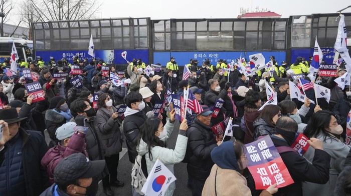 Supporters of impeached South Korean President Yoon Suk Yeol gather as police officers block the road to the Constitutional Court in Seoul, South Korea, Tuesday, Jan. 21, 2025. The letters read 