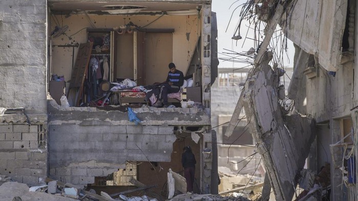 Pulang ke Reruntuhan Rumah, Warga Gaza Kais Sisa-sisa Barang Mahmoud al-Azazi sits in a bedroom inside a destroyed home a day after the ceasefire deal between Israel and Hamas came into effect, in Rafah, southern Gaza Strip, Monday, Jan. 20, 2025,(AP Photo/Abdel Kareem Hana)