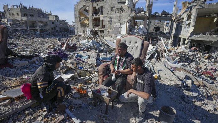 Mahmoud al-Azazi sits in a bedroom inside a destroyed home a day after the ceasefire deal between Israel and Hamas came into effect, in Rafah, southern Gaza Strip, Monday, Jan. 20, 2025,(AP Photo/Abdel Kareem Hana)