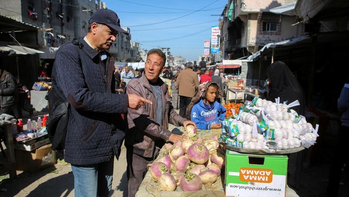 Aktivitas Ekonomi di Gaza Mulai Berdenyut A Palestinian boy looks on as people shop for food at a street market, following a ceasefire between Israel and Hamas, in Khan Younis in the southern Gaza Strip, January 21, 2025. REUTERS/Hatem Khaled