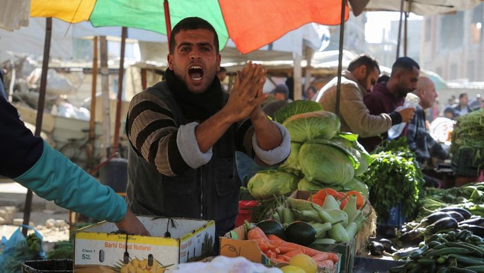 A Palestinian boy looks on as people shop for food at a street market, following a ceasefire between Israel and Hamas, in Khan Younis in the southern Gaza Strip, January 21, 2025. REUTERS/Hatem Khaled