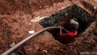 Para pekerta sibuk memasukkan kabel ke dalam galian.  