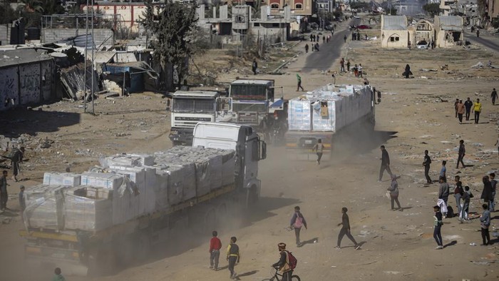Truk Bantuan Kemanusiaan Masuk Gaza, Langsung Diserbu Warga Humanitarian aid trucks enter through the Kerem Shalom crossing from Egypt into the Gaza Strip, as a ceasefire deal between Israel and Hamas went into effect, in Rafah, Tuesday, Jan. 21, 2025. (AP Photo/Jehad Alshrafi)