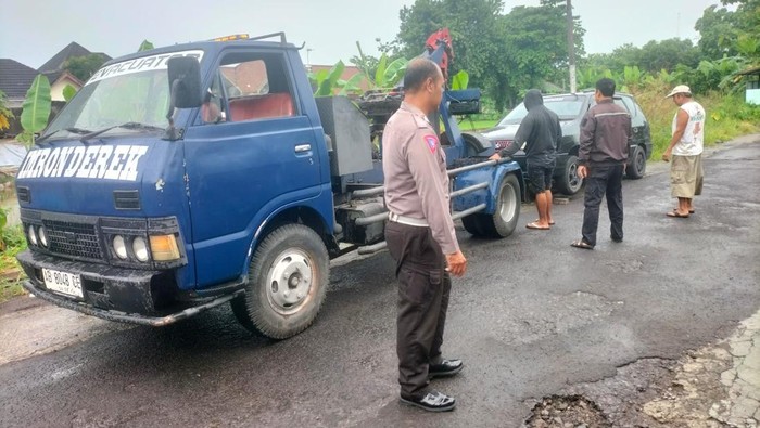 Anggota Polsek Depok Timur menderek mobil KIA Carens yang parkir sebulan lebih di depan toko bakpia di Condongcatur, Kabupaten Sleman, Kamis (23/1/2025) pagi.