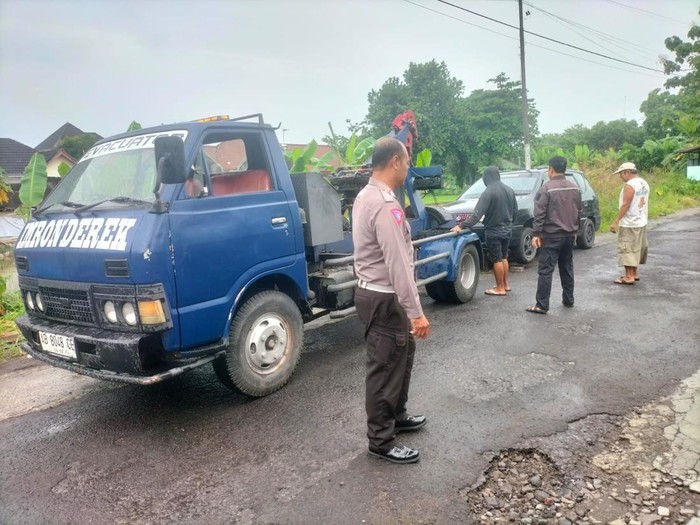 Anggota Polsek Depok Timur menderek mobil KIA Carens yang parkir sebulan lebih di depan toko bakpia di Condongcatur, Kabupaten Sleman, Kamis (23/1/2025) pagi.