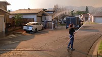Warga yang rumahnya masih utuh berinisiatif menyemprotkan rumah mereka dengan air.  