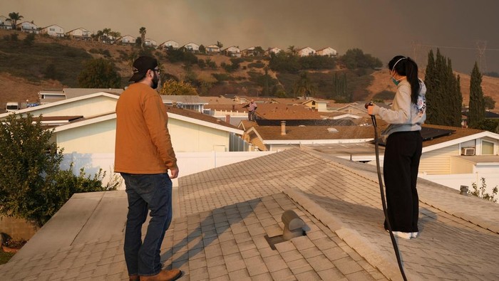 Antisipasi Ikut Terbakar, Warga California Semprot Rumahnya Pakai Air Tania Carbajal sprays down her home with water as the Hughes Fire burns, in Castaic, California, U.S., January 22, 2025. REUTERS/Joel Angel Juarez