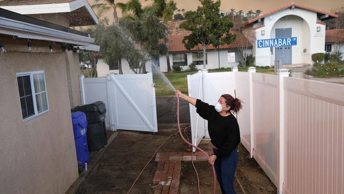 Antisipasi Ikut Terbakar, Warga California Semprot Rumahnya Pakai Air Tania Carbajal sprays down her home with water as the Hughes Fire burns, in Castaic, California, U.S., January 22, 2025. REUTERS/Joel Angel Juarez