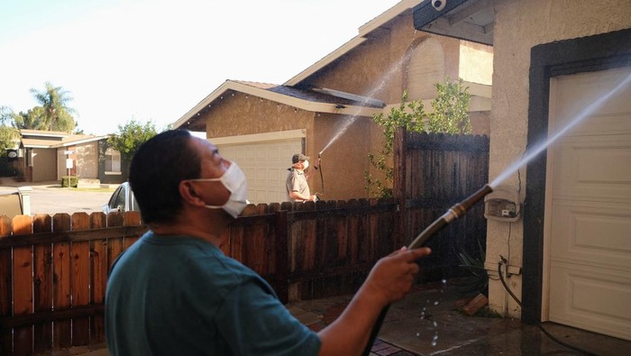 Antisipasi Ikut Terbakar, Warga California Semprot Rumahnya Pakai Air Tania Carbajal sprays down her home with water as the Hughes Fire burns, in Castaic, California, U.S., January 22, 2025. REUTERS/Joel Angel Juarez