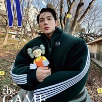Ada pula penampilan Im Siwan memakai round neck zip-up jacket dengan detail puff pada bagian bahu. Warna jaketnya serasi dengan seragam peserta permainan bertahan hidup Squid Game. Tampak vinyl figure Younghee keluaran Kaws bikin salfok. Foto: dok. W Korea
