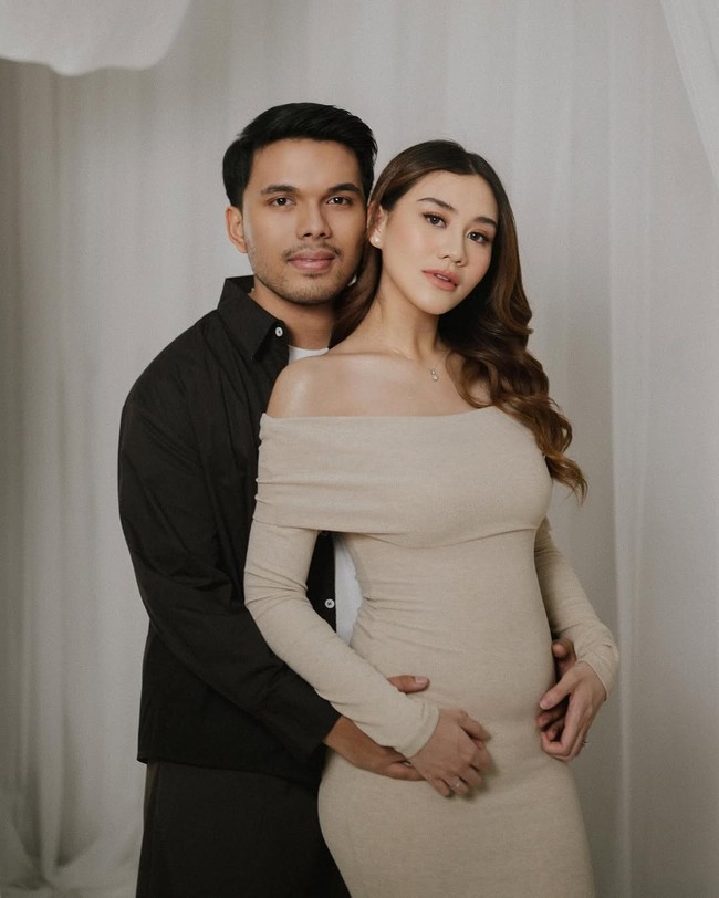 Mendampingi sang ibu hamil, Thariq Halilintar tampil serasi dengan busana bernuansa monokrom. Adik YouTuber Atta Halilintar ini mengenakan kemeja dan celana hitam dipadu t-shirt putih. Foto: Instagram/@aaliyah.massaid