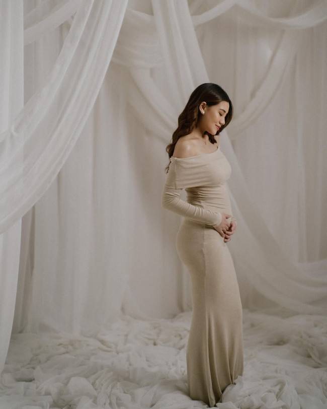 Gaun pun memperlihatkan baby bump Aaliyah yang mulai menonjol. “From two to three.. coming soon, our little bundle of joy🤍,” tulis wanita 22 tahun ini di caption foto. Foto: Instagram/@aaliyah.massaid