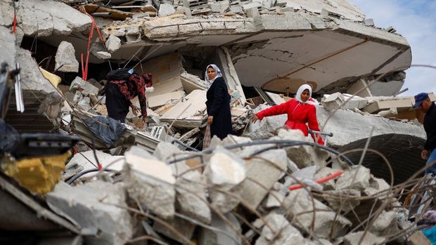 Palestinians sit near the rubble of buildings destroyed during the Israeli offensive, following a ceasefire between Israel and Hamas, in Rafah in the southern Gaza Strip, January 22, 2025. REUTERS/Mohammed Salem     TPX IMAGES OF THE DAY