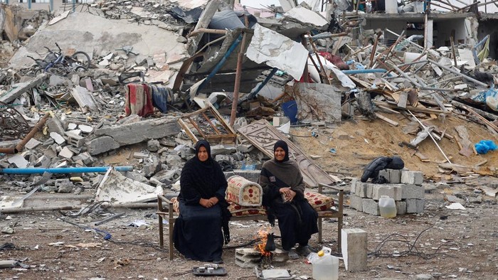 Palestinians sit near the rubble of buildings destroyed during the Israeli offensive, following a ceasefire between Israel and Hamas, in Rafah in the southern Gaza Strip, January 22, 2025. REUTERS/Mohammed Salem     TPX IMAGES OF THE DAY
