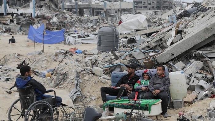 Palestinians sit near the rubble of buildings destroyed during the Israeli offensive, following a ceasefire between Israel and Hamas, in Rafah in the southern Gaza Strip, January 22, 2025. REUTERS/Mohammed Salem     TPX IMAGES OF THE DAY