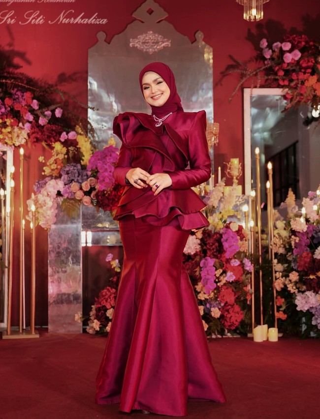 Sesuai dengan tema dekorasinya, Siti tampil cantik kenakan dress berwarna merah marun. Dress tersebut memiliki model duyung pada bagian bawah dan ruffle pada bahu hingga pinggangnya. Foto: Instagram/@ctdk