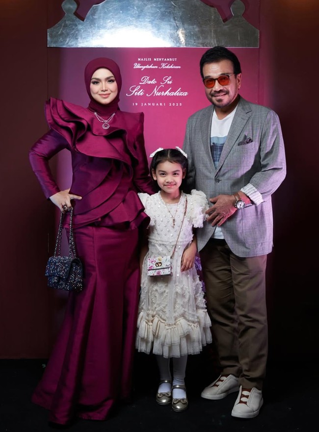 Anak pertama Siti Nurhaliza, Siti Aafiyah, juga tampak hadir dan berpose bersama kedua orangtuanya. Sang putri tampil mengenakan dress berwarna putih dipadukan dengan sepasang sepatu berwarna keemasan. Foto: Instagram/@ctdk