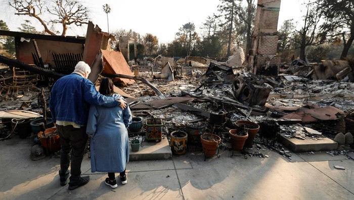 Warga California Meratapi Rumahnya yang Ludes Terbakar Hilda Dawley and her husband, Greg Dawley, carry belongings they found after their home burned in the Eaton Fire, in Altadena, California, U.S. January 19, 2025. REUTERS/Fred Greaves