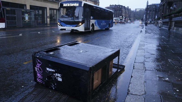A bus drives around bins blown over by the winds from Storm Eowyn on Princes Street, Edinburgh, Scotland, as Storm Eowyn hits the country, Friday Jan. 24, 2025. (Jane Barlow/PA via AP)