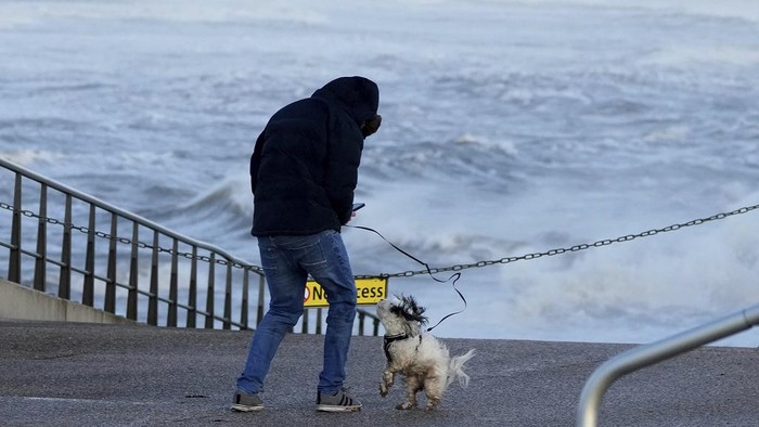 A man with his dog braves the wind as Storm Eowyn hits the country in Cleveleys, near Blackpool, England, Friday, Jan. 24, 2025.(AP Photo/Jon Super)