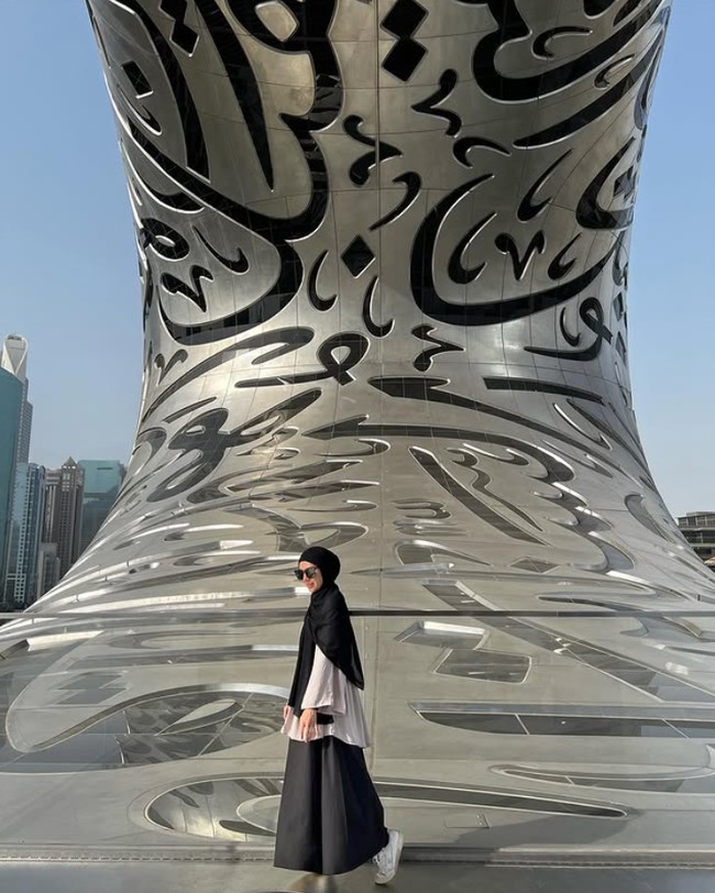 Ratna Galih tampil casual ketika berada di Museum of the Future di Dubai, dengan menggunakan hijab pashmina hitam, blouse cream dan bawahan hitam. Agar terasa nyaman saat traveling, Ratna Galih lebih memilih memakai sneakers. Foto: Dok. Instagram @ratnagalih.