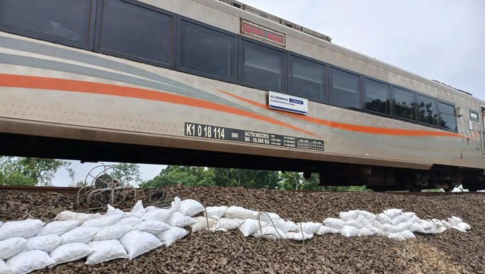 Kereta api melintas dengan kecepatan terbatas di jalur rel yang tergerus banjir di Kabupaten Grobogan, Jumat (24/1/2025) pagi.
