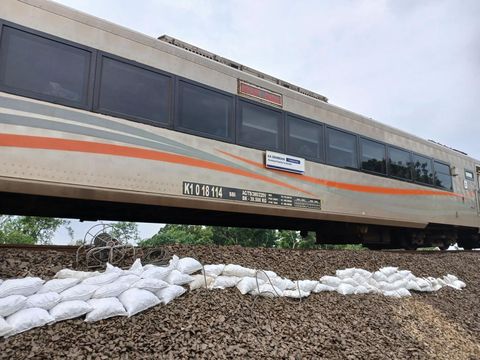 Kereta api melintas dengan kecepatan terbatas di jalur rel yang tergerus banjir di Kabupaten Grobogan, Jumat (24/1/2025) pagi.